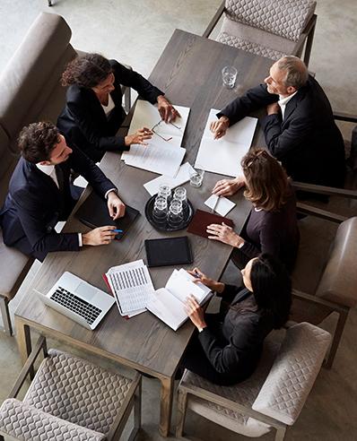 Fachexpert*innen für Regulatory Compliance Consulting Services sitzen an einem Tisch.